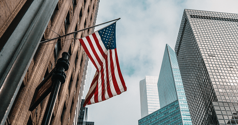 American flag with buildings