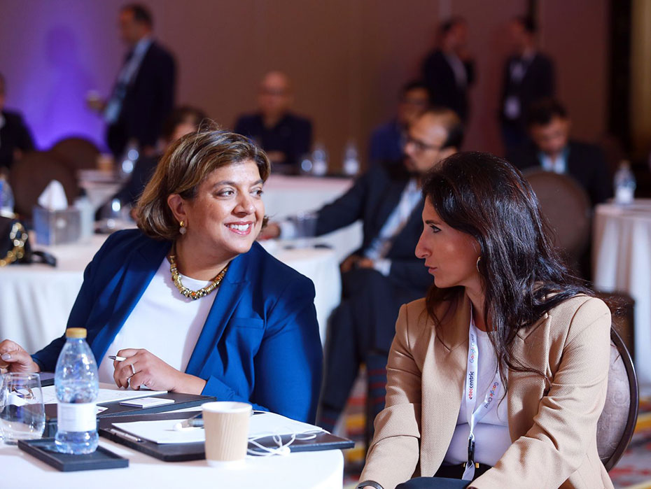 Two women are sitting at a table, smiling and talking to each other