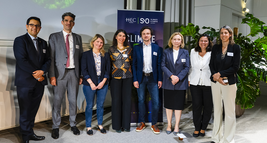A group of eight people, including co-organizers and panelists, stand together and pose for a photo during the 'Climate Day' event at HEC Paris