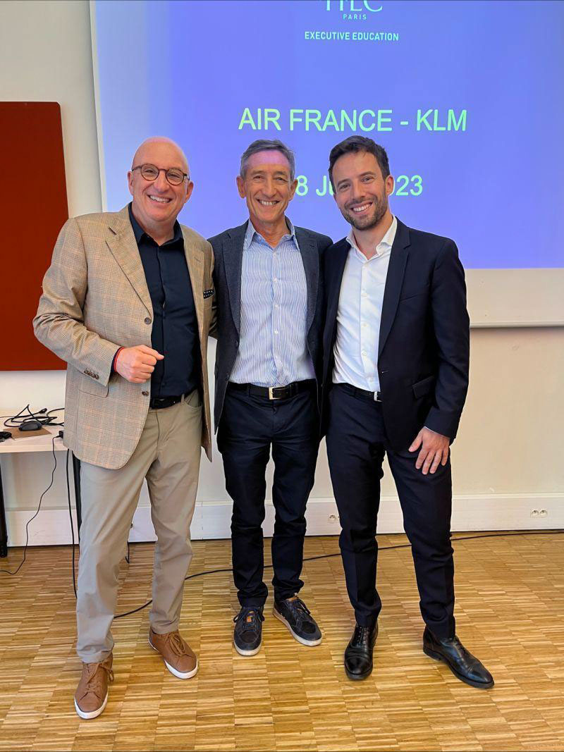 three men posing together in a classroom or conference room setting, with 