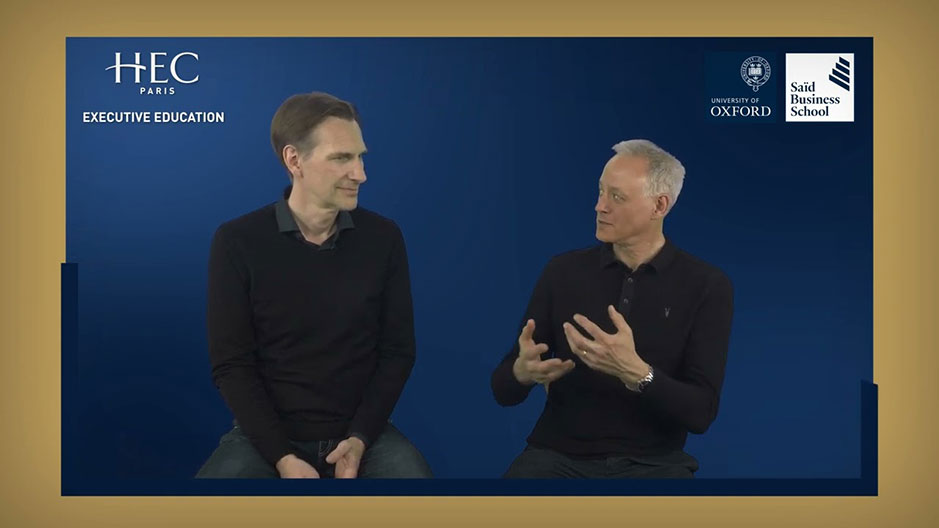 Two men in black shirts are sitting next to each other, with logos from HEC Paris, Oxford University, and Saïd Business School in the background.