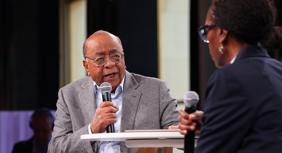 Mo Ibrahim speaking during a panel discussion at the Paris Peace Forum, engaging in dialogue with another participant on stage