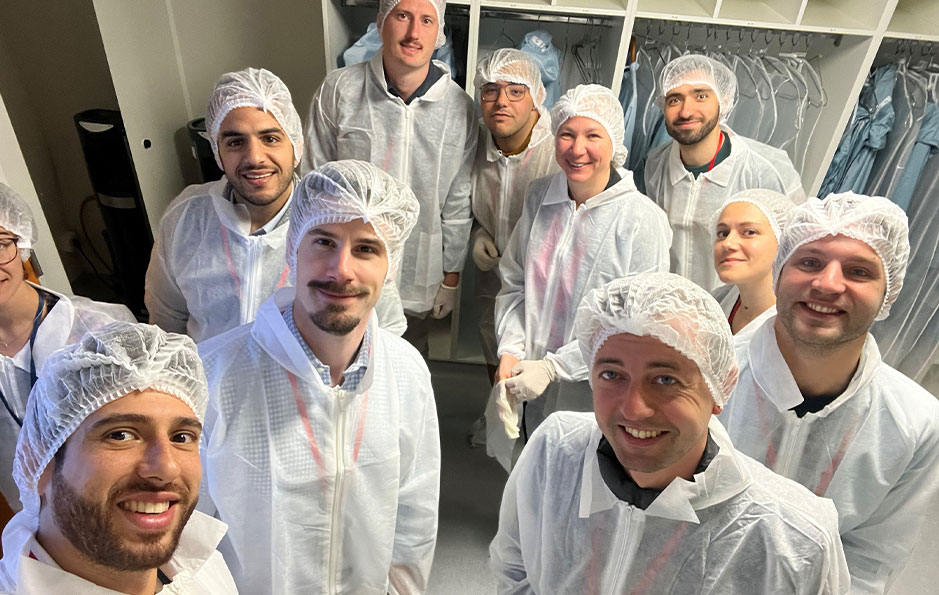 Groupe de personnes en tenues de protection blanches, souriant et posant pour une photo lors d'une visite immersive des installations de HECTAR