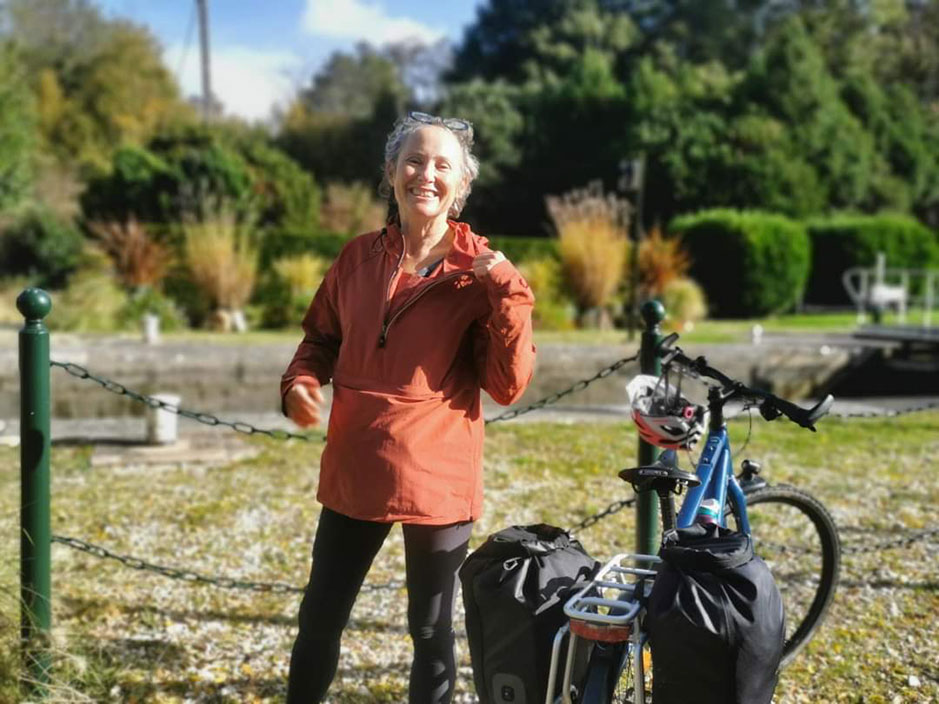 SDmiling woman standing next to her bicycle, which is equipped with panniers