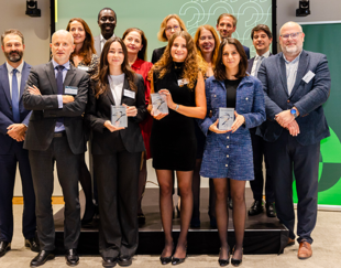 award recipients and organizers during the Allen & Overy Shearman event, with participants holding trophies and posing on stage