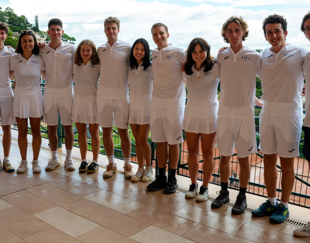 Groupe d'étudiants d'HEC Paris en tenue de tennis blanche posant ensemble lors de l'HEC Clay Court Challenge 2024, avec vue sur la mer et les collines en arrière-plan.